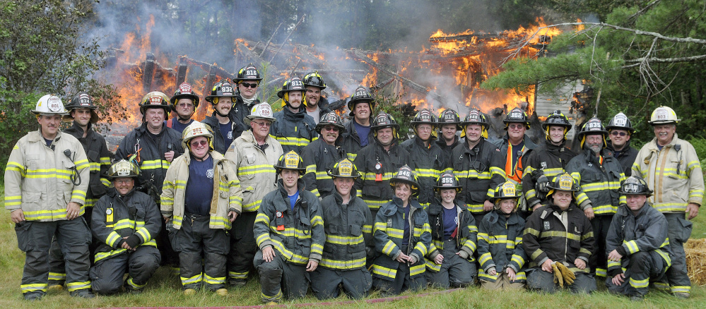Members of the Monmouth Fire Department pose Sunday at a home they burned during a training exercise.