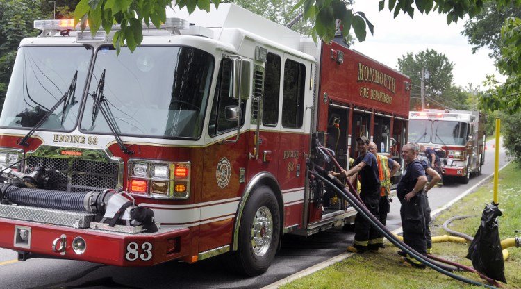 Monmouth Fire Department members draw water from the company's new rescue pumper Sunday while suppressing the controlled burn of a home in town during a training exercise. The volunteer company practiced interior fire suppression while using its two new fire engines, according to Chief Dan Roy.