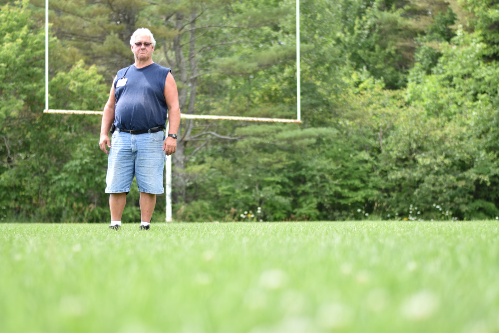 Jeff Sheive, facilities director at Oakland-based Regional School Unit 18, stands on a football field behind Messalonskee Middle School, one of the fields where the district is testing the strategy of overseeding as part of a U.S. Department of Agriculture-funded research project on improving school turf.