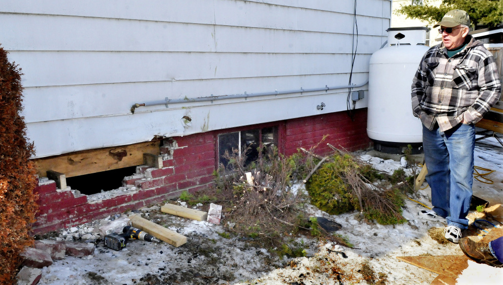 Waterville homeowner Roland Hallee looks over the damage to a basement wall on March 6 that occurred when a vehicle driven by Sueann M. Call, 47, of Waterville, crashed into the building.