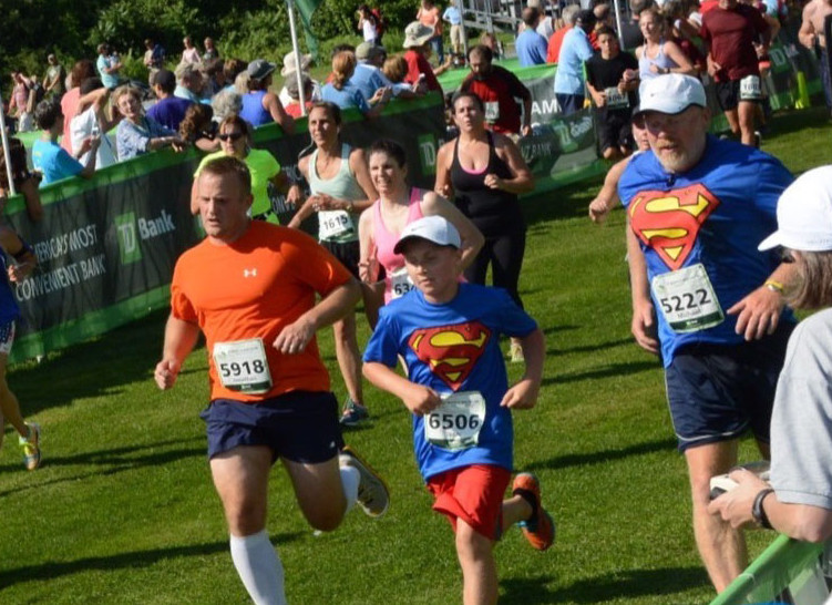 Mike Gammon, wearing bib No. 5222, and his son, Isaac, center, both of Randolph, cross the finish line at the 2015 TD Beach To Beacon 10K. The father-son duo are running in their second consecutive B2B together on Saturday.