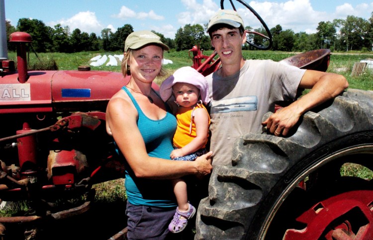 Farmers Johanna Burdet and Jarret Haiss hold their daughter, Tiger, at their Moodytown Gardens farm in Palmyra last week. Younger farmers are part of a growing trend, experts say.