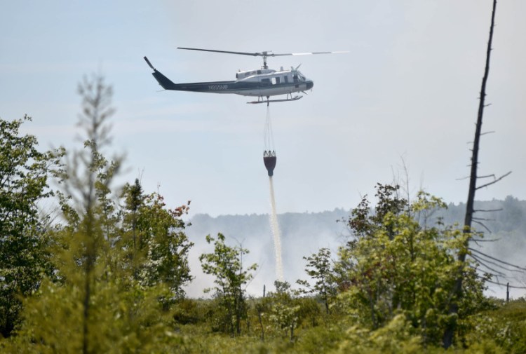 A forest service helicopter attacks a wildfire Tuesday near Mud Pond in China. The fire burned about 2 acres near the Winslow-China town boundary over five hours. Firefighters were back at the site Wednesday to monitor hot spots.