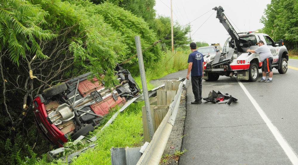 Tow truck operators pull a vehicle out of the ditch Saturday on Route 3 in South China.