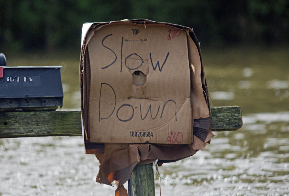 A sign tells motorists to slow down to avoid pushing water into homes near Holden, La.