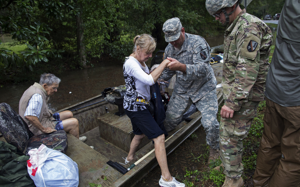 Members of the Louisiana Army National Guard rescue people from rising floodwater Sunday near Walker, La., after heavy rains inundated the region. With several rivers still rising, there is danger of more flooding.
