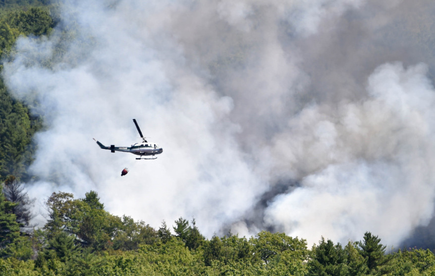 A forest service helicopter attacks a wildfire near Mud Pond on the China-Winslow border last Tuesday. The hot spots from the fire are finally out after flaring for a few days afterwards. Officials are looking for information about how the fire started, including anyone trespassing in the area that day.
