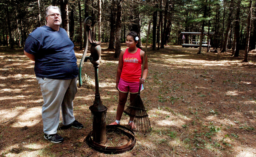 Bill Owens and daughter Jasmine stand beside a spring well Monday in the woods off Four Mile Square Road in North Anson, where performers will take the stage in the background for the Billy's Belly Bluegrass and Folk Music Competition this Sunday.