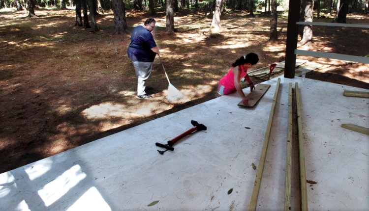 Bill Owens and daughter Jasmine work around the stage area in the woods Monday off Four Mile Square Road in North Anson, where performers will take the stage for the Billy's Belly Bluegrass and Folk Music Competition this Sunday.