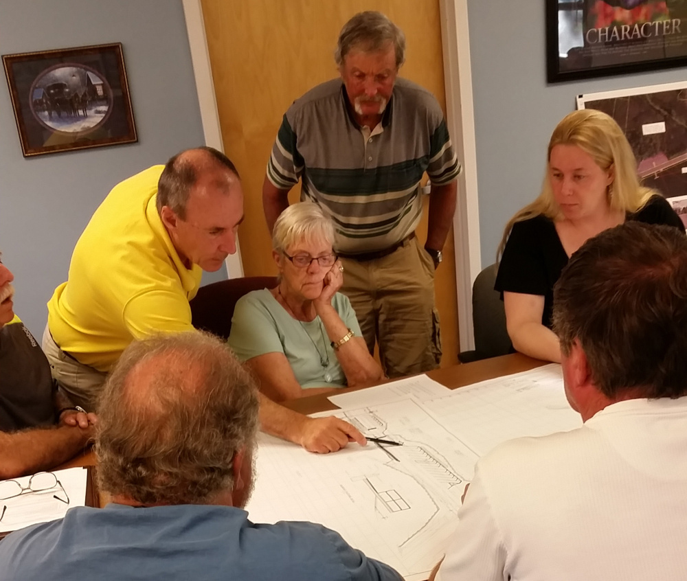 Engineer Mark McCluskey, left, explains renderings of possible improvements to China's causeway as Paul Mitnik, standing, and Selectwoman Joann Austin, seated center, both members of the TIF committee, and TIF committee Chairman Amber McCallister, right, listen.