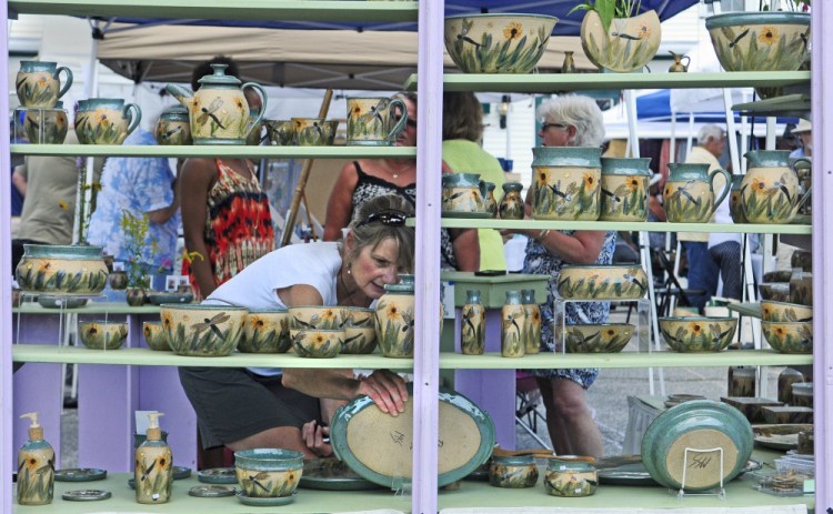 Sue Firlotte, of North Monmouth, picks up a platter in The Potter's House booth during the Winthrop Summer Festival on Aug. 15, 2015, in downtown Winthrop.