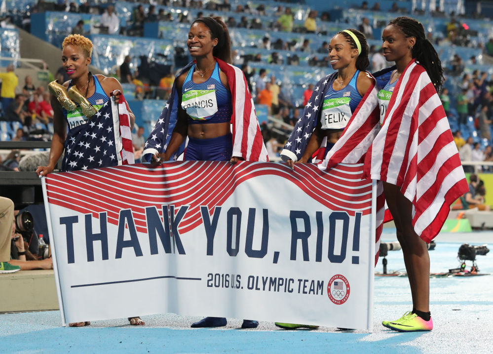 United States' Courtney Okolo, Natasha Hastings, Phyllis Francis and Allyson Felix hold a sign and wear their nation's flag after winning the gold in the women's 4x400 meter relay during athletics competitions at the Summer Olympics inside Olympic stadium Saturday in Rio de Janeiro, Brazil.
