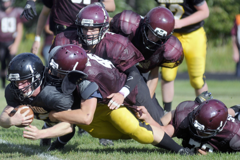 A Maranacook ball carrier gets tackled by a host of Nokomis defenders during a scrimmage Monday afternoon in Readfield.