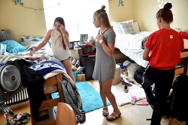 Mackenzie Carlow, left, settles in to her dormitory room Friday with her roommates Taylor Peno, center, and Ashlyn Parker at Thomas College in Waterville.