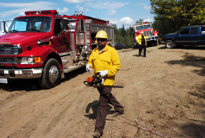 Firefighters from several area departments responded to a woods fire Tuesday off Gray Road in Vassalboro. Winslow Fire Department Assistant Chief Charles Theobald, background, directs trucks to the scene. The fire, which burned until Wednesday morning, was sparked by logging equipment and fueled by dry conditions, a forest ranger said Wednesday.