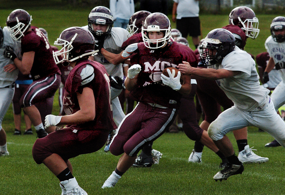 Staff photo by David Leaming 
 MCI running back Adam Bertrand evades John Bapst defenders during a scrimmage in Pittsfield last week.