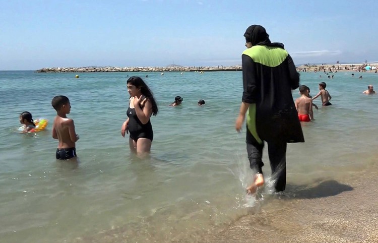 Nissrine Samali wades  into the sea wearing a burkini, a wetsuit-like garment that also covers the head, in Marseille, France, ion Aug. 4, 2016. Associated Press