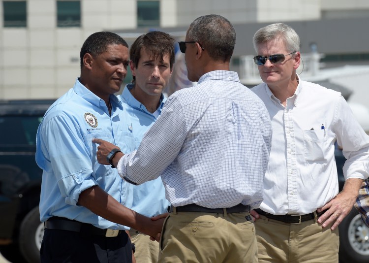 President Barack Obama is greeted by, from left, Rep. Cedric Richmond, D-La., Rep. Garret Graves, R-La., and Sen. Bill Cassidy, R-La., after arriving on Air Force One at Baton Rouge Metropolitan Airport Tuesday. Susan Walsh/Associated Press