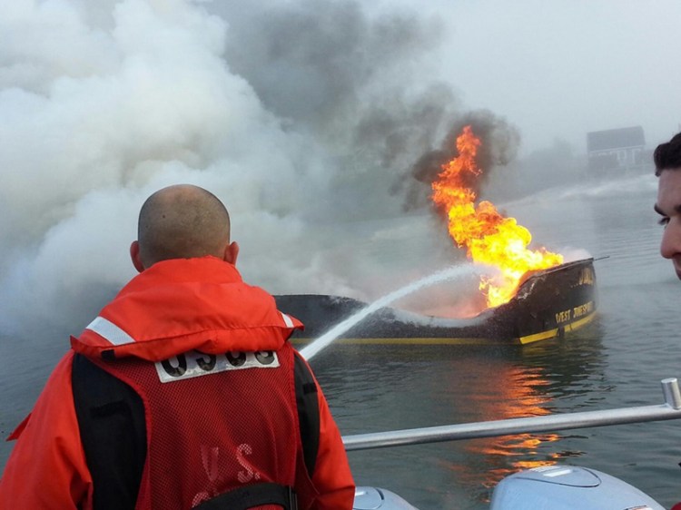 Coast Guard Petty Officer 3rd Class Cory Langston fights the boat fire from the Coast Guard 29-foot response boat.