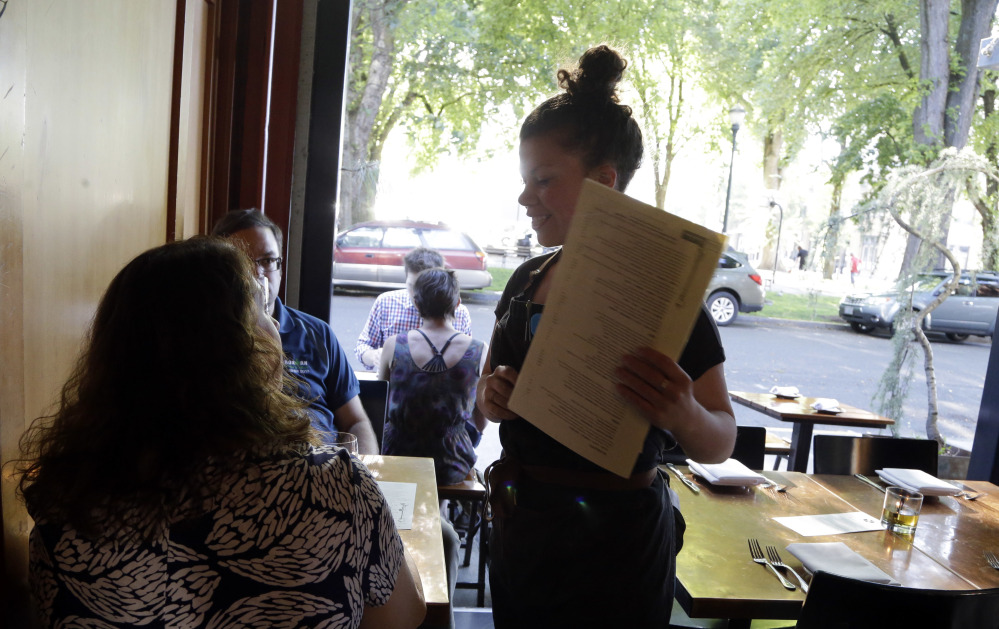 Caroline Pond – a sous chef, server and bartender – talks with customers at Park Kitchen, where shifts were vamped so most employees work full-time and in multiple roles. Nearly all the servers left because of the changes.