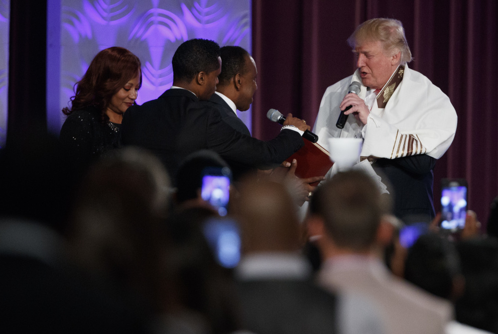 Donald Trump wears a prayer shawl as he is presented with a gift during a service Saturday at Great Faith Ministries International, a predominantly black church in Detroit.
