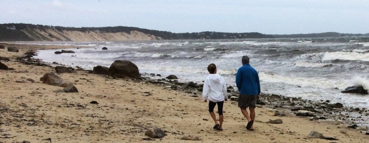A couple walk along Sagamore Beach in Bourne, Mass., on Monday as Hermine whips up heavy surf on Cape Cod Bay and churns hundreds of miles out in the Atlantic Ocean.