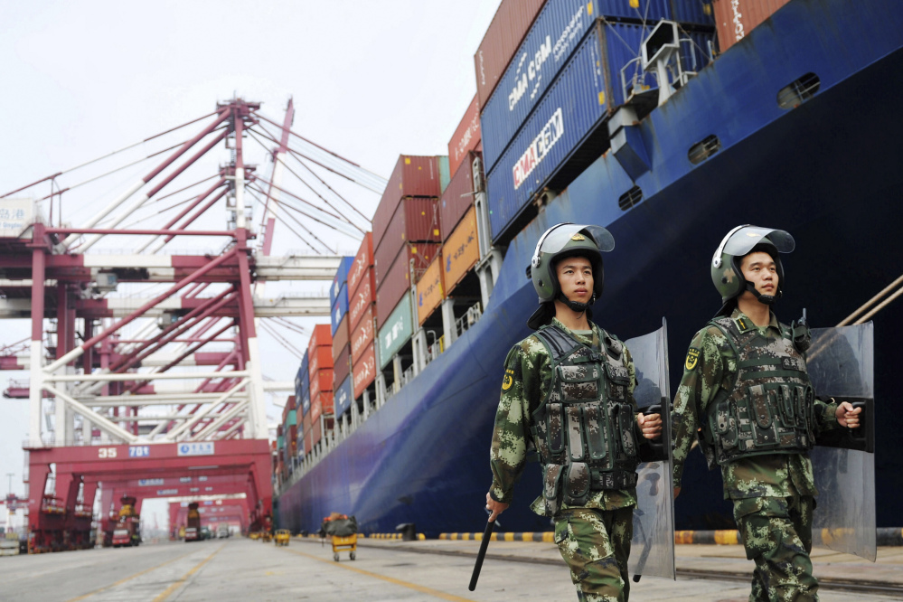 China's paramilitary police patrol as containers are loaded on to a cargo ship for export at a port in Qingdao in east China's Shandong province Thursday. China's exports rose in August for the first time in two years.