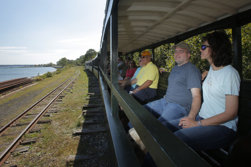 Laura and Franco Chiaramonte and other passengers take in the view as the Maine Narrow Gauge Railroad travels along the Portland waterfront last week. The railroad and museum pull in more than 30,000 visitors a year.