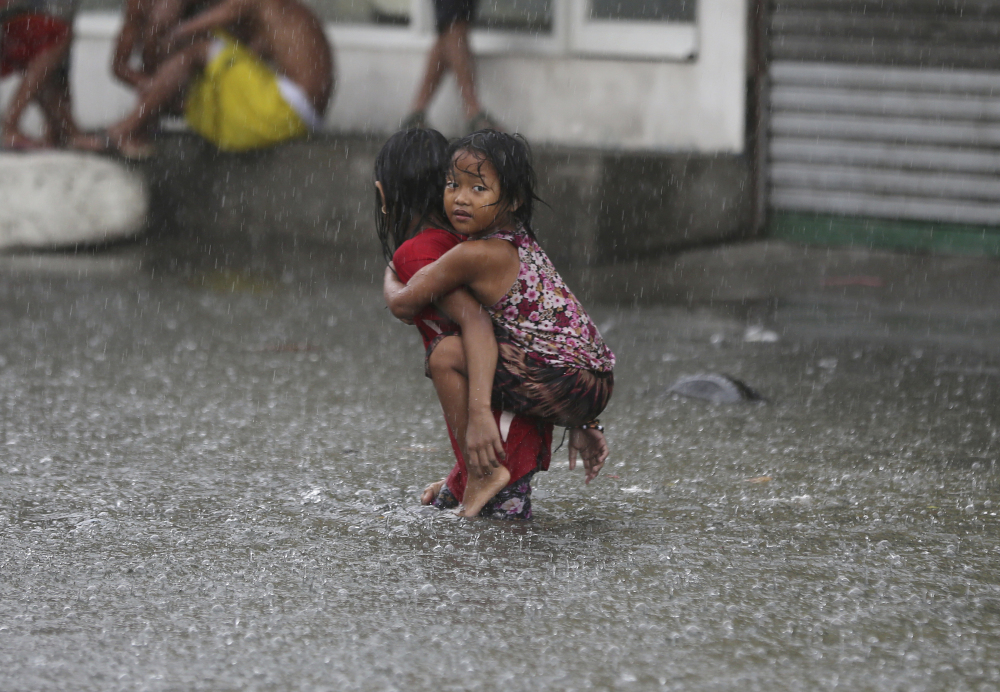 A Filipino girl is carried along a flooded road on July 8 in suburban Mandaluyong, east of Manila, Philippines, as downpours intensify while Typhoon Nepartak exits the country. 