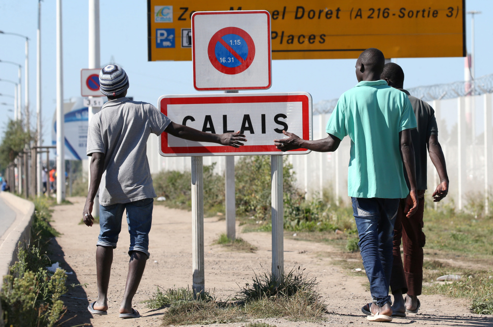 Migrants pass by a road near the camp called "the Jungle" in Calais, France. Camp conditions are "not acceptable" and "extremely difficult" French President Francois Hollande said.