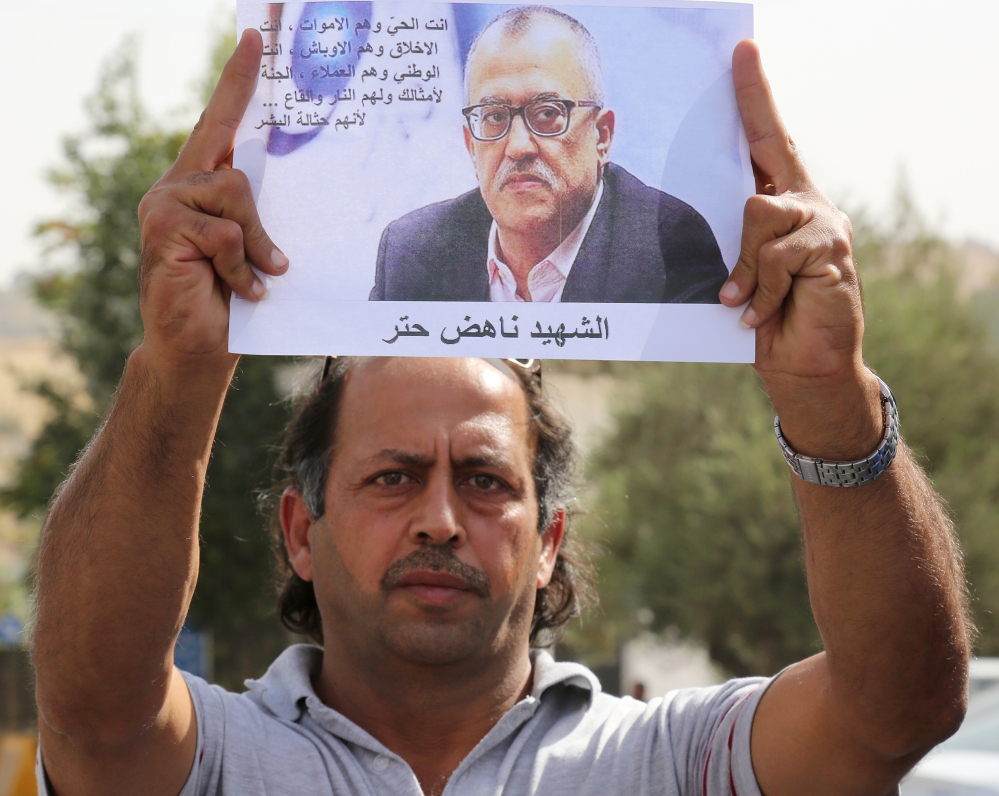 A man holds a picture of Jordanian writer Nahed Hattar, who was shot dead Sunday in front of the courthouse where he was on trial.