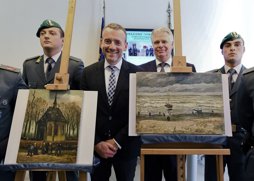 Director of Amsterdam's Van Gogh Museum Axel Rueger, center, stands next to the paintings "Congregation leaving the Reformed Church of Nuenen," left, and the 1882 "Seascape at Scheveningen" by Vincent Van Gogh, during a news conference in Naples, Italy, on Friday. The paintings were stolen from the museum in 2002.