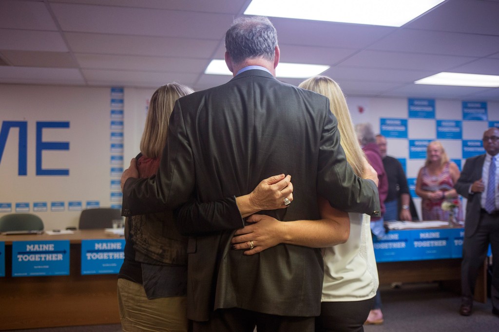 Two volunteers pose for a photo with Tim Kaine at the campaign office in downtown Portland.