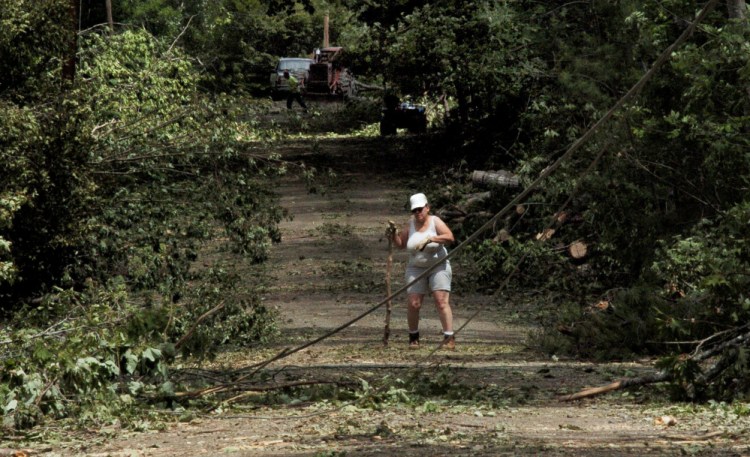 Ballard Road resident Luanne Paquin works to clear brush July 19 around utility wires and broken poles on the closed road in St. Albans, a day after a microburst cut a path of destruction through several towns, damaging property and downing trees. The U.S. Department of Agriculture is offering possible financial help for tree farmers and others affected by the storm.