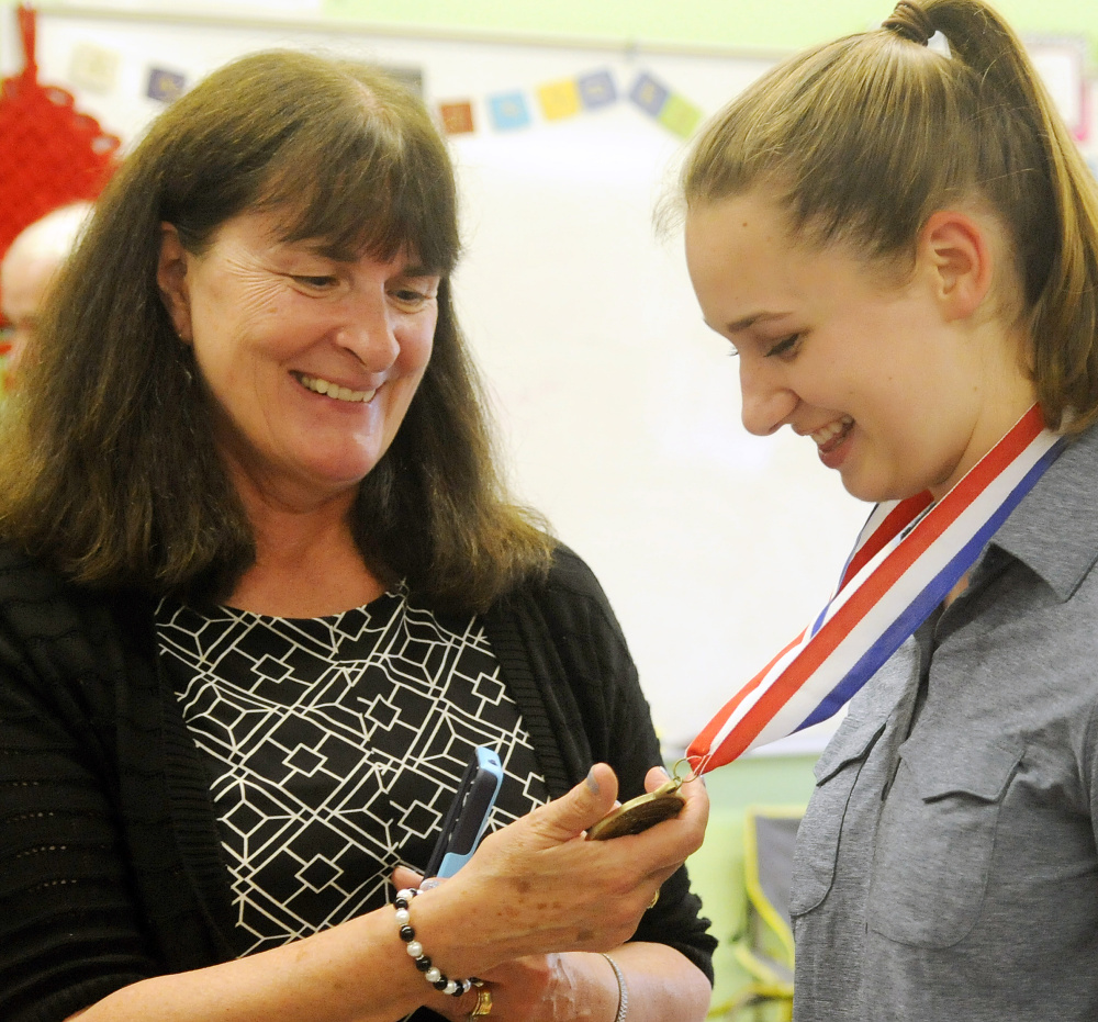 Monmouth Academy English teacher Christine Arsenault examines a medal presented to student Maddie Amero on Thursday for making a film with classmates that won best presentation from Maine at the National History Day Competition in Washington, D.C.