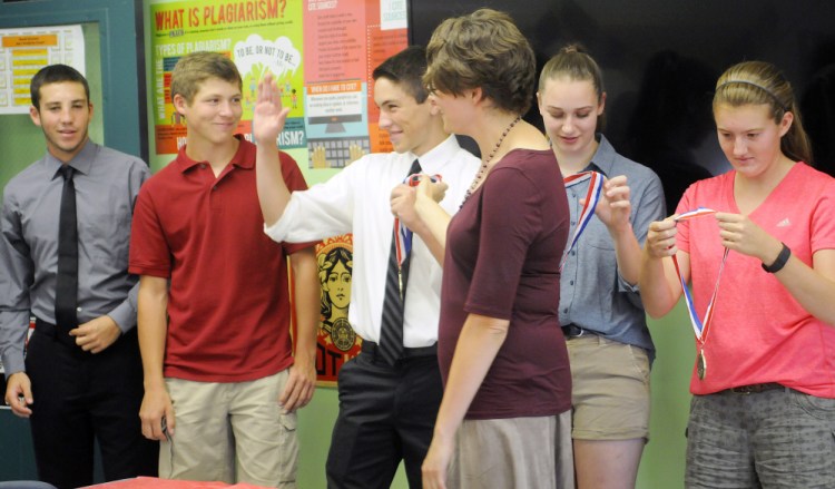 Monmouth Academy students Devon Poisson, left, Dylan Goff, Cody Roy, Maddie Amero, second from right, and Abbey Allen, right, receive medals Thursday from teacher Jocelyn Gray, center, at the school. The juniors won best presentation from Maine at the National History Day Competition in Washington, D.C. for a documentary about the Acadian deportation from Canada in the 1700s.