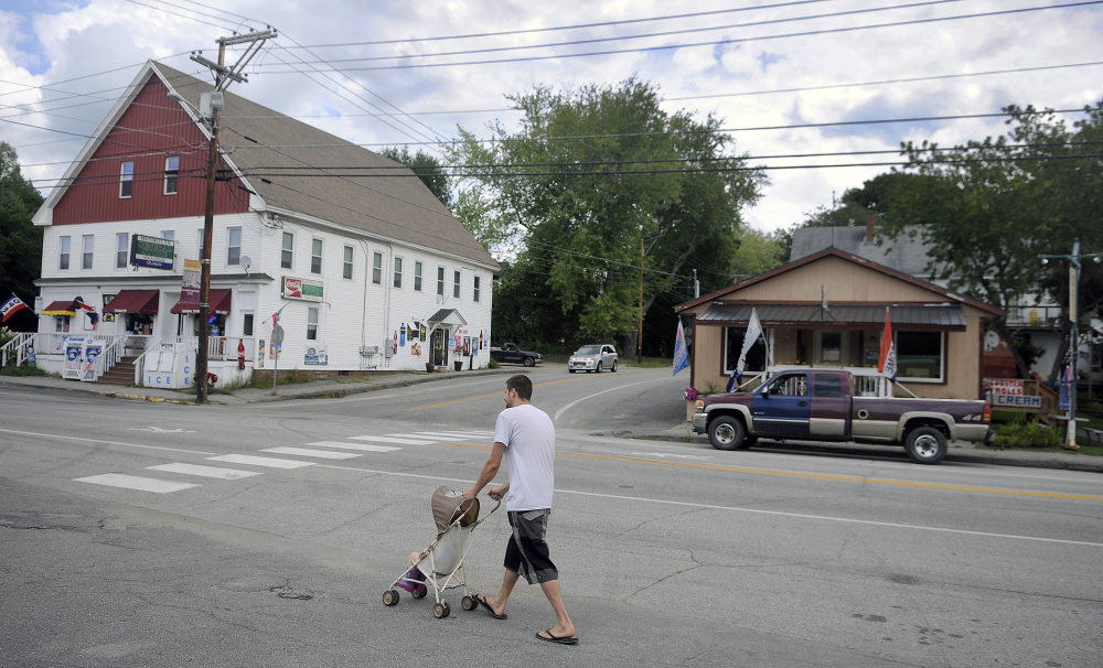 Justin Caouette pushes his daughter, Emily, down Main Street in Monmouth on Thursday. Monmouth selectmen have approved placing an item before voters on the November ballot to add five empty lots to the downtown, tax increment financing district.