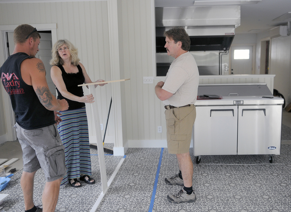 Dave Poulin, right, and Lisa Taber Poulin work Thursday with contractor Jason Landry on a counter in the cafe the couple are building at the former Al's Pizza in Augusta. The couple plan to name the business Fat Cat's Cafe.