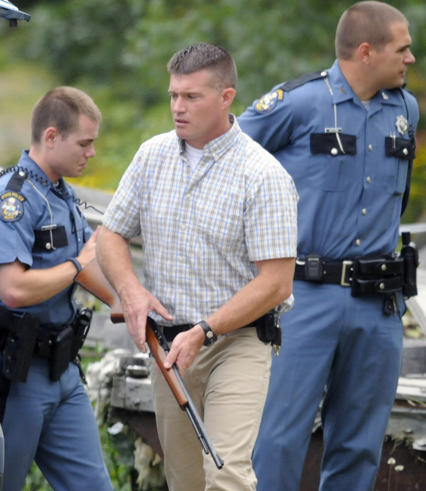 Maine State Police Detective Elisha Fowlie secures a .22-caliber rifle Thursday that Douglas Burl, 54, allegedly fired at a man outside Burl's Chelsea residence. Burl was charged with reckless conduct with a dangerous weapon and criminal threatening with a dangerous weapon by troopers after the 10 a.m. incident. No injuries were reported.