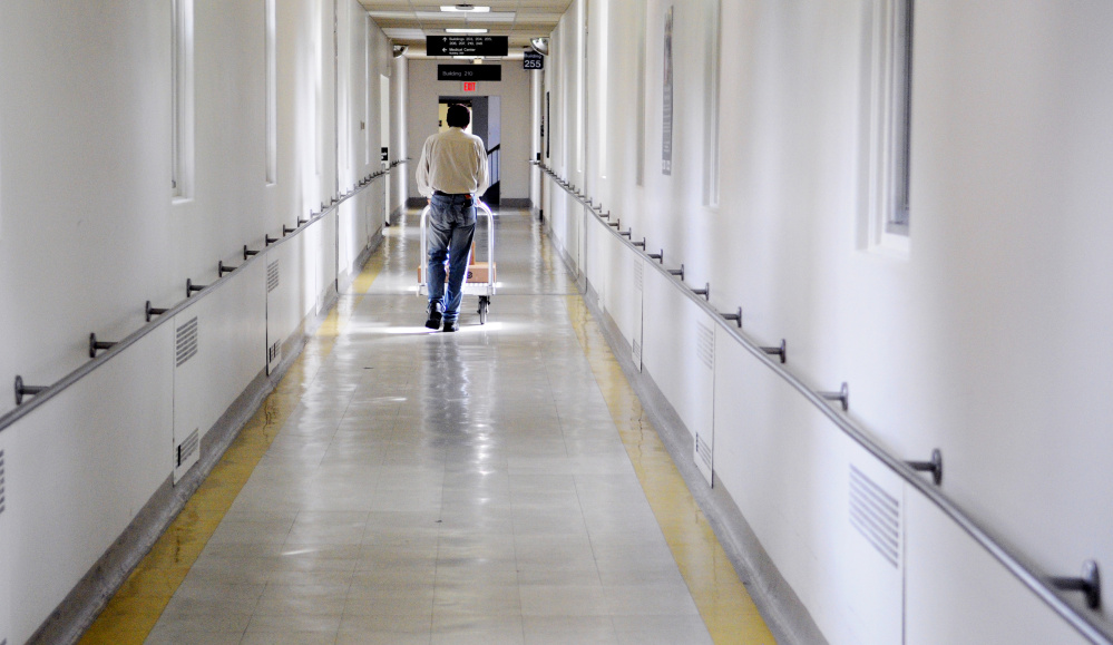 Volunteer John Hurt, of Augusta, rolls a cart down a hallway on Thursday between buildings at the VA Maine Healthcare Systems-Togus. Hurt, an Army veteran, volunteers to make deliveries and sanitize equipment several days a week. There is a system of tunnels and passageways between many of the buildings on campus.