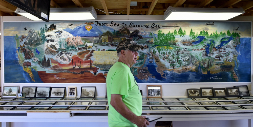 Buddy Frost, president of the Clinton Historical Society, sits Friday in front of a mural painted by Viva Chamberlain in 1976 that's on display at the Clinton Lions Agricultural Fair in Clinton.