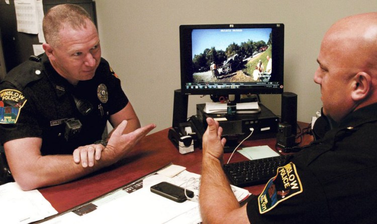 Winslow police officer John Veilleux, left, and Lt. Josh Veilleux discuss a recent car accident the department covered while viewing a video from the scene and taken with a department body camera used by an officer. 