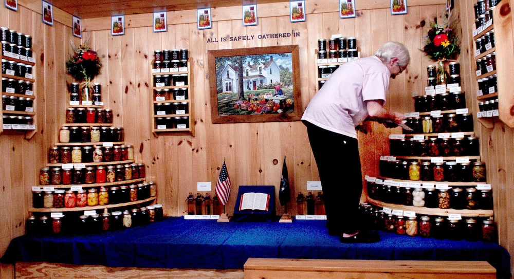 Karen Locke sets up a display of canned foods and other items for the Chesterville Grange 20 exhibit in preparation for the Farmington Fair, which begins Sunday.