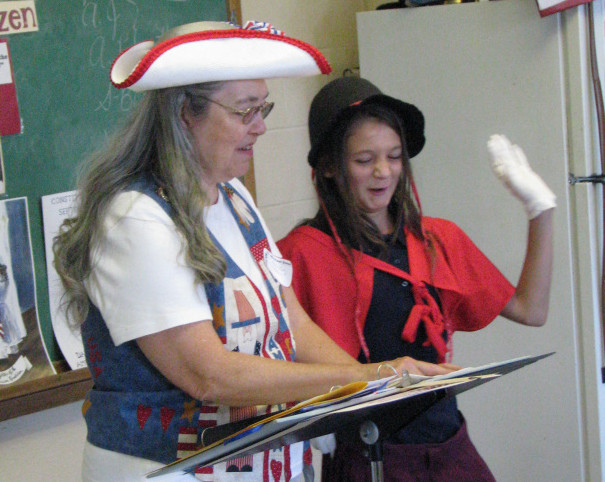 Sixth-grader Ava Nadeau, right, reads from the script with the Constitution Lady Bonnie Wilder during a Constitution Week celebration at St. Michael School in Augusta.