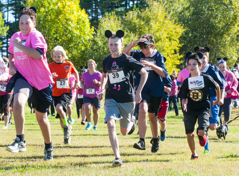 Participants, many wearing pink and mouse ears, sprint off from the starting line at the Miles Across Maine for Breast Cancer Awareness on Saturday at University of Maine of Augusta.