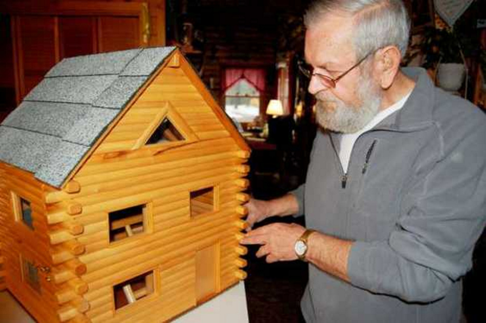 Lenny Ellis of New Vineyard unlocks the front one of his one-of-a-kind 
 toy log homes he builds out of wooden dowels. He is hoping to find a 
 way to give one of his creations to President Barack Obama's daughters.
