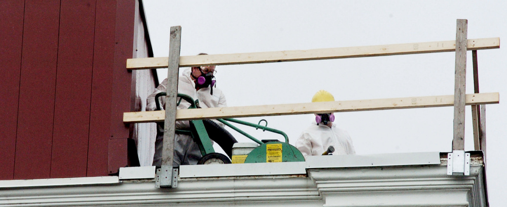 Workers wearing face masks remove the roof from Waterville City Hall on Tuesday as part of a $125,000 roof replacement project.