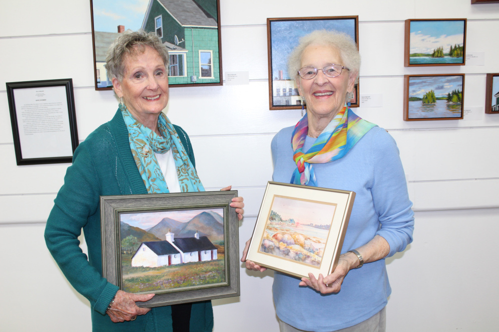 In a photo provided by Mary Morrison, Waterville Area Art Society members Patricia Binette, left, and Pauline Turner hold up their original paintings that will be displayed Oct. 6 at a Winslow Public Library reception.