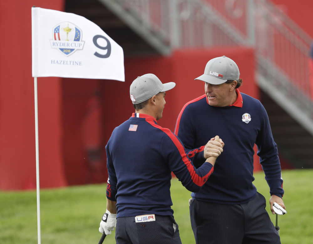 Phil Mickelson celebrates with teammate Rickie Fowler after Fowler chipped in on the ninth to win the hole during a Ryder Cup foresomes match Friday at Hazeltine National Golf Club in Chaska, Minnesota.