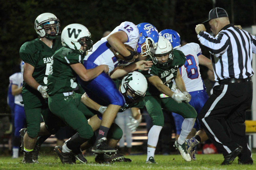 Oak Hill High School quarterback Matthew Strout gets brought down by Winthrop/Monmouth's Antonio Meucci, left, and a host of Rambler defenders during first-half action Friday night in Winthrop.